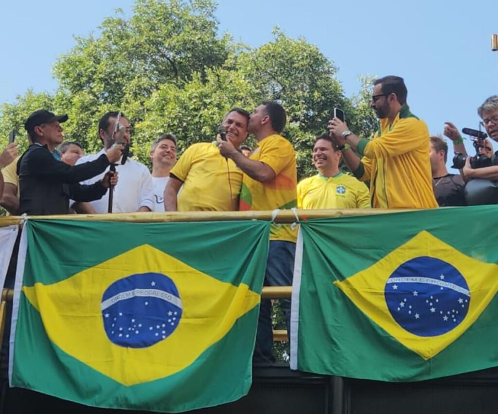 O beijo de Flávio em Jair, no palanque do evento de Alexandre Ramagem, na Tijuca