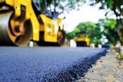 Rua sendo pavimentada por rolos compressores amarelos.