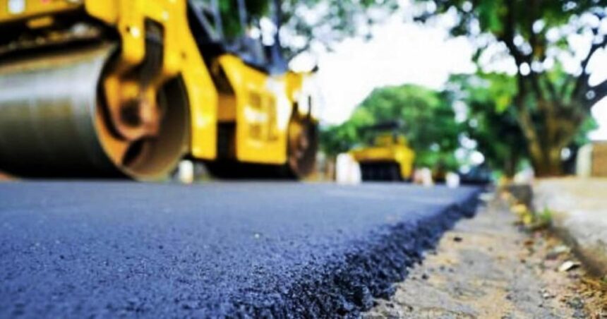 Rua sendo pavimentada por rolos compressores amarelos.