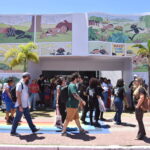 pessoas caminhando em frente a entrada de uma feira literária