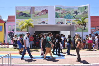 pessoas caminhando em frente a entrada de uma feira literária