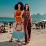 duas modelos, uma de vestido e outra de conjunto, posam em frente a praia do arpoador, no rio de janeiro