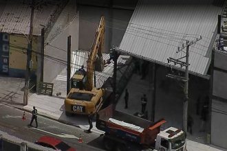 A demolição de prédio comercial construído de forma irregular acontece na esquina da Avenida dos Democráticos com Rua Unanos, em Bonsucesso.