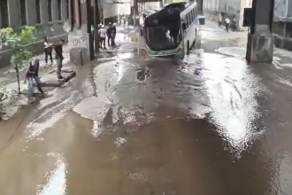 Ônibus fica preso em buraco na Rua Figueira de Melo, em São Cristóvão, após vazamento de esgoto