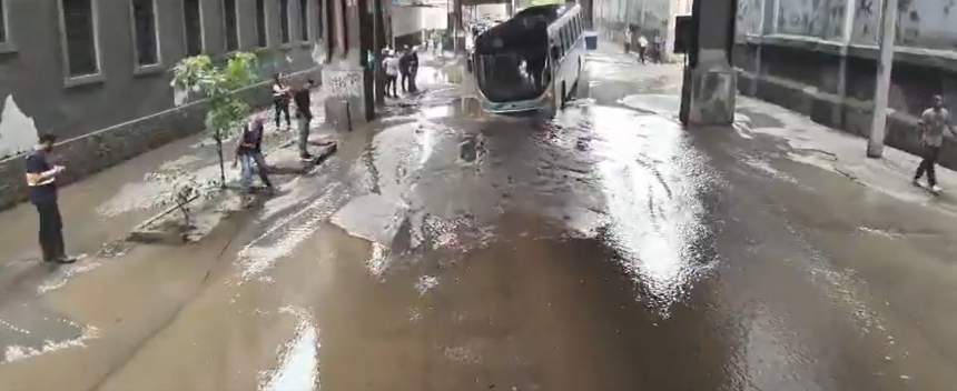 Ônibus fica preso em buraco na Rua Figueira de Melo, em São Cristóvão, após vazamento de água