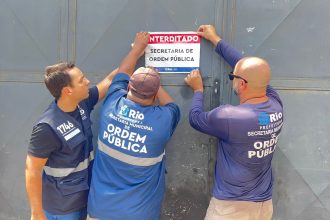 Agentes da Seop colam adesivo em portão