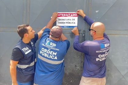 Agentes da Seop colam adesivo em portão