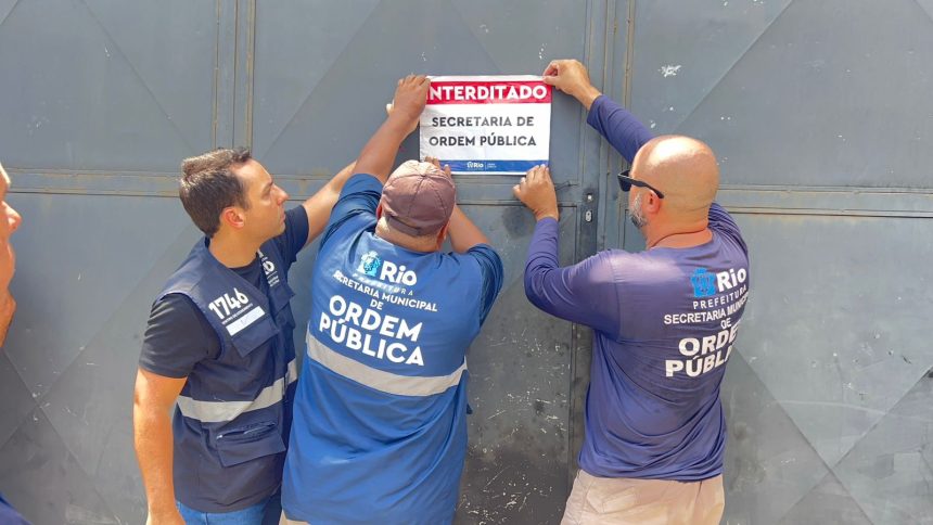 Agentes da Seop colam adesivo em portão