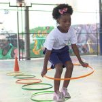 Criança brinca com bambolê no Programa Escola de Férias