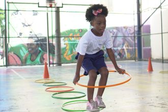 Criança brinca com bambolê no Programa Escola de Férias