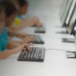 Alunos utilizam computadores em ambiente escolar; MPRJ recomendou a adoção obrigatória da educação digital e midiática nas escolas de Campos dos Goytacazes a partir de 2026.