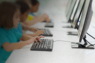 Alunos utilizam computadores em ambiente escolar; MPRJ recomendou a adoção obrigatória da educação digital e midiática nas escolas de Campos dos Goytacazes a partir de 2026.