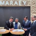 Marcelo Freixo, presidente da Embratur, assina documento durante a FITUR, em Madri, ao lado do prefeito de Maricá, Washington Quaquá, e representantes do setor turístico.