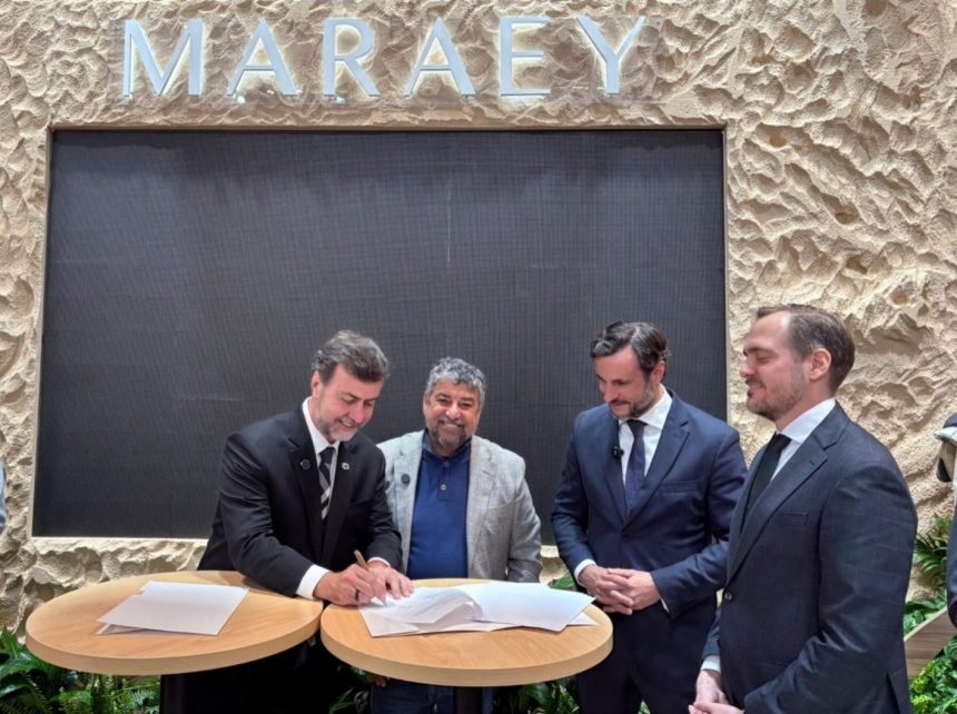 Marcelo Freixo, presidente da Embratur, assina documento durante a FITUR, em Madri, ao lado do prefeito de Maricá, Washington Quaquá, e representantes do setor turístico.