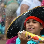 Criança brinca com espuma durante bloco infantil no Rio; programação do Carnaval 2026 inclui desfiles mirins na Sapucaí e opções para famílias em diferentes regiões da cidade.