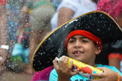 Criança brinca com espuma durante bloco infantil no Rio; programação do carnaval 2026 inclui desfiles mirins na Sapucaí e opções para famílias em diferentes regiões da cidade.