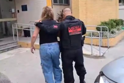 Ana Paula Alexandre Novello, acusada de gerenciar bingo clandestino, sendo conduzida por agente do MPRJ à delegacia