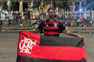 Ex-goleiro Bruno segurando bandeira do Flamengo em frente ao Maracanã