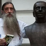 Foto de Nelsinho ao lado de um busto do pai, Nelson Rodrigues
