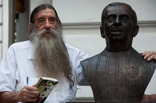 Foto de Nelsinho ao lado de um busto do pai, Nelson Rodrigues