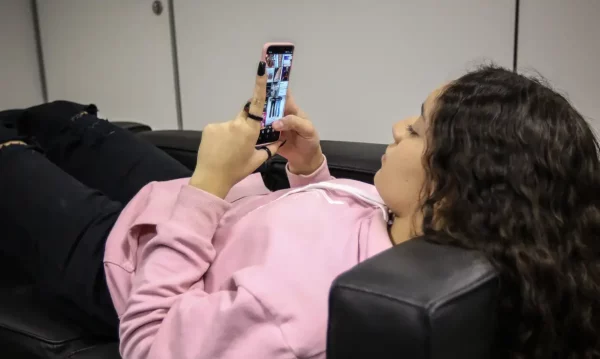 Adolescente usando celular; vítima de violência psicológica digital