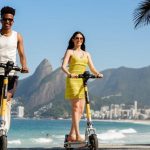 Homem e mulher passeiam no Rio em patinetes elétricos