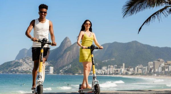 Homem e mulher passeiam no Rio em patinetes elétricos