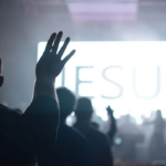 Imagem de pessoas com as mãos para o alto em uma igreja evangélica