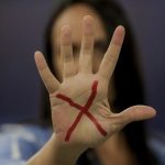 Mulher com um "X" desenhado na mão Pacto Estadual Contra o Feminicídio