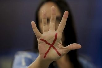 Mulher com um "X" desenhado na mão Pacto Estadual Contra o Feminicídio