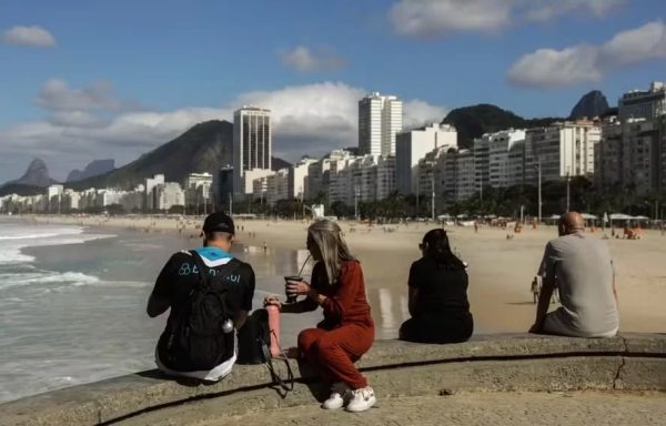 Sol e casaco: cariocas e turistas aproveitam o sábado de tempo estável na mureta da Praia do Leme, na Zona Sul do Rio. Fim de semana terá céu aberto, máxima de 28°C e madrugadas frias, com mínima de 13°C na capital.