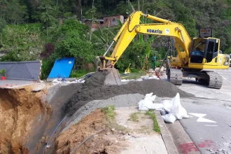 Escavadeira cobre cratera formada à margens da rodovia BR-040, em Petrópolis