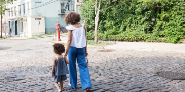 Mãe e filha andando de mãos dadas na rua